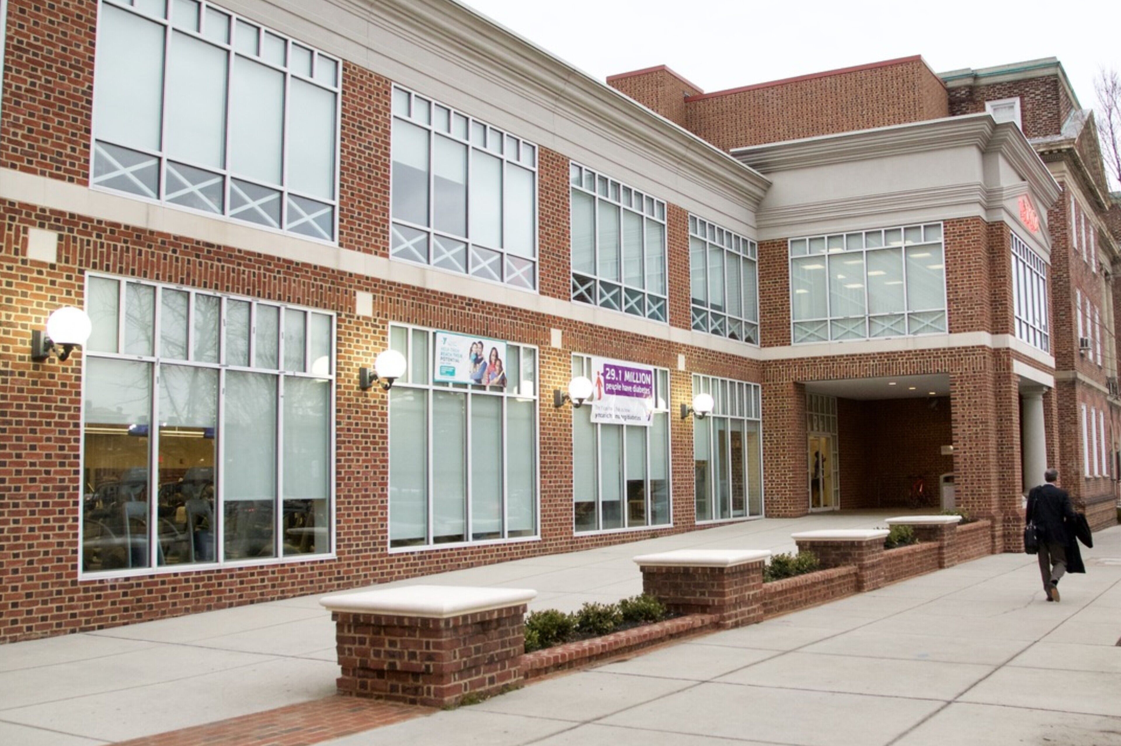 A brick building with large windows and a covered entrance.