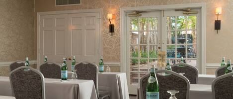 Un comedor con mesas dispuestas para el servicio, sillas y botellas de agua Pellegrino.
