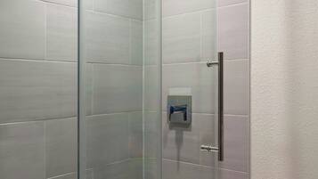 Een moderne douchecabine met een glazen deur, bedieningspaneel en metalen handgreep.