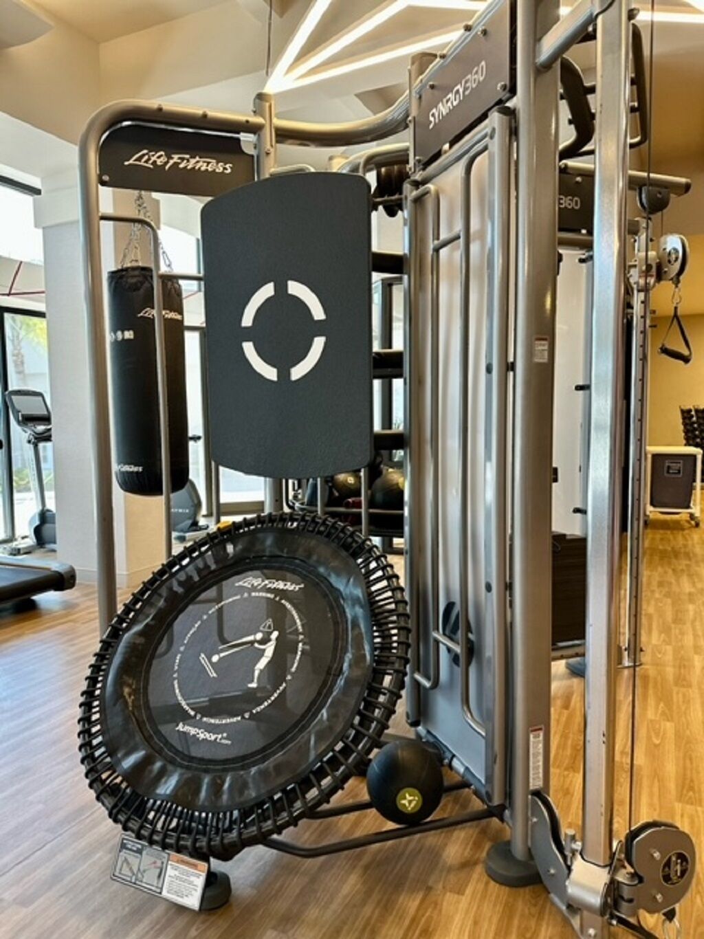 Een fitnessruimte met een cirkelvormig trainingsapparaat, gewichtstapel en bokszak.