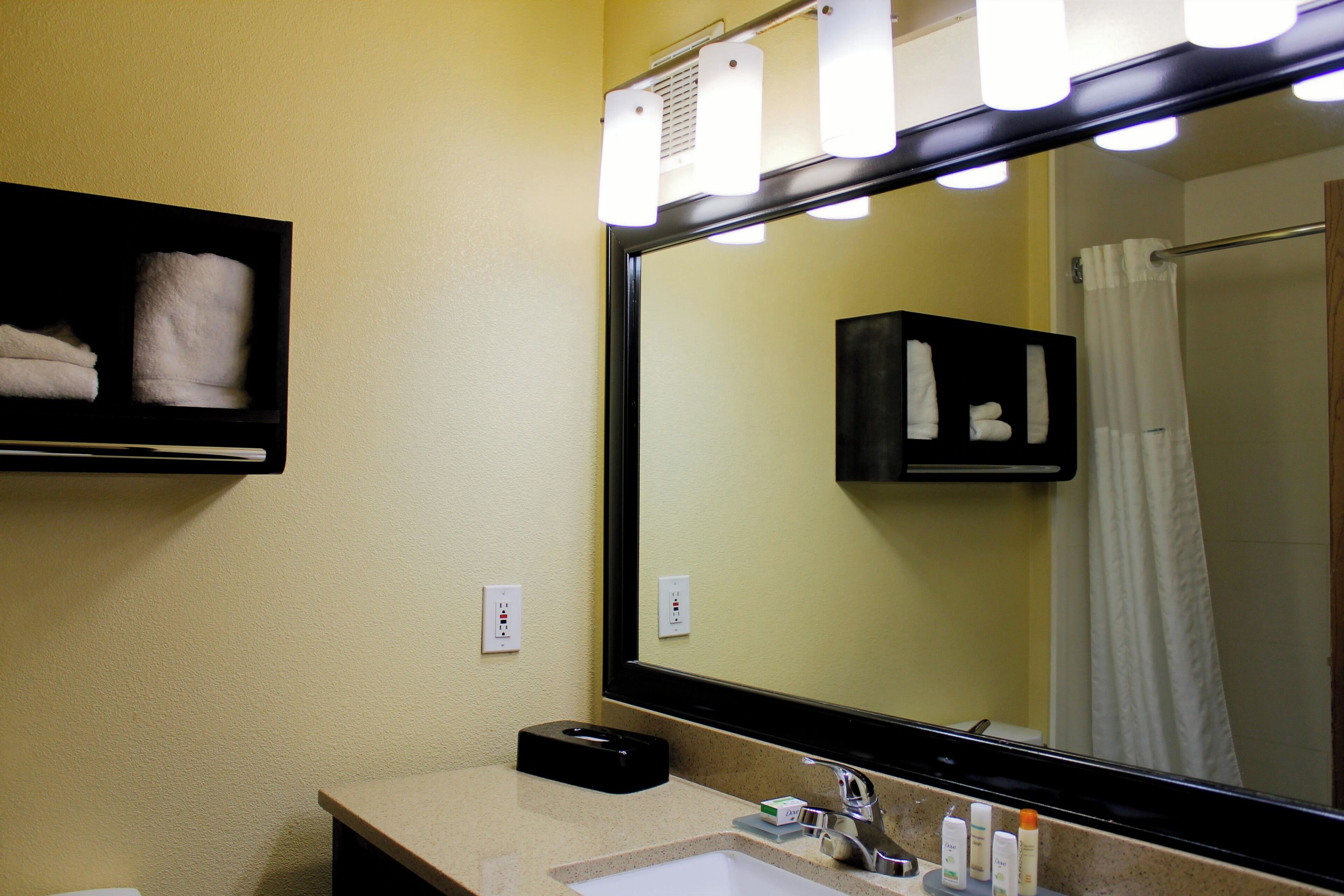 A bathroom with a large mirror, a sink, and a towel rack.