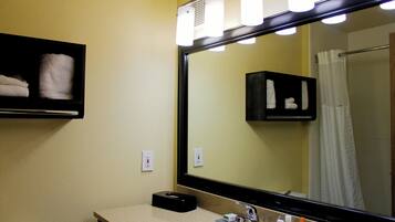 A bathroom with a large mirror, a sink, and a towel rack.