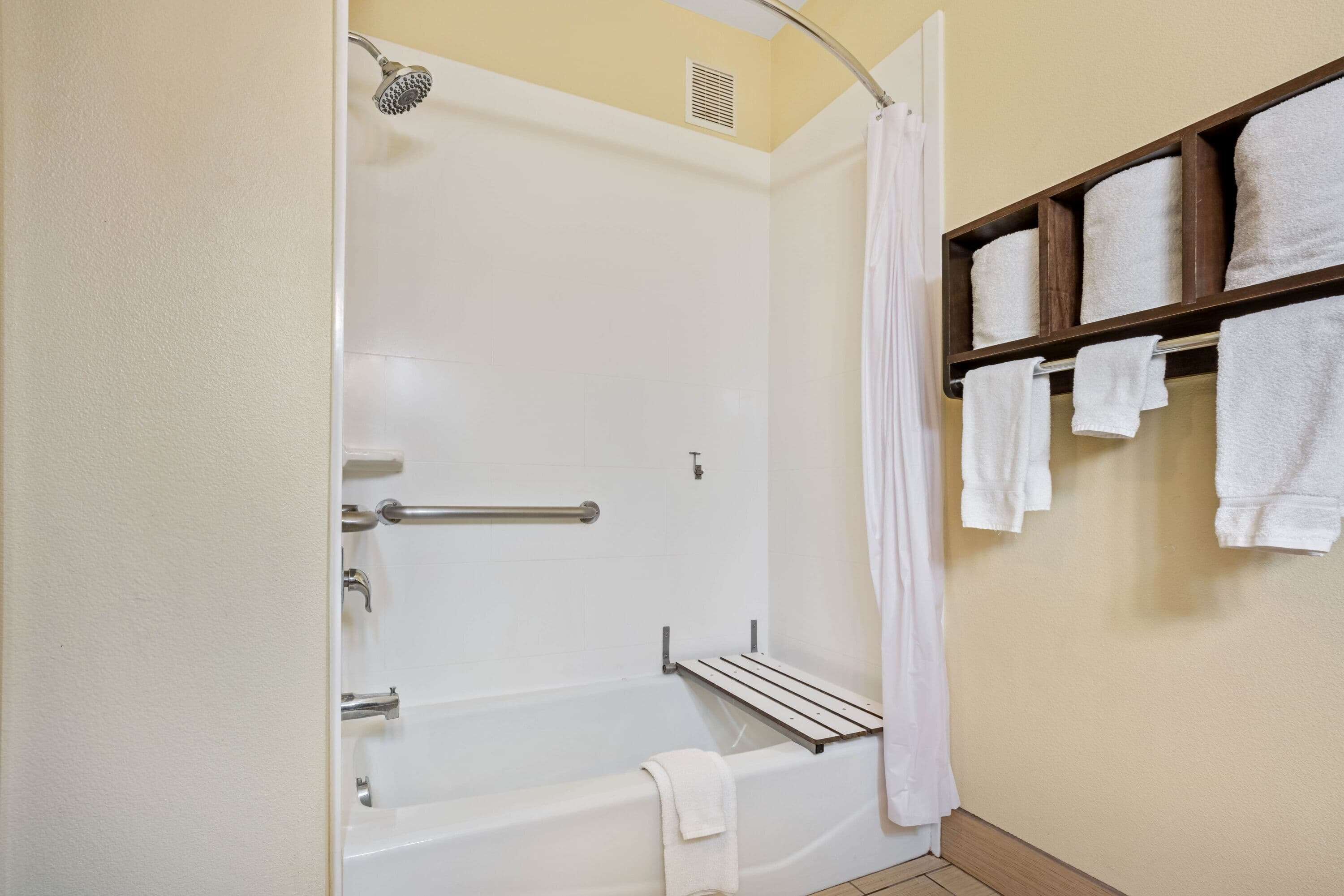 A bathroom with a bathtub, a shower, and a towel rack with towels.