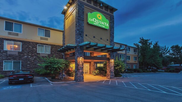 Edificio de La Quinta Inn & Suites con fachada de piedra, un letrero iluminado grande y un estacionamiento.