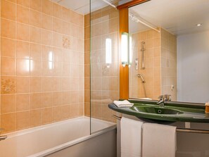 Een badkamer met een bad, een groene wastafel en een spiegel.