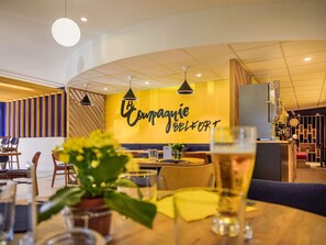 Een modern restaurantinterieur met een gebogen plafond, hanglampen en een opvallend wandbord met de tekst 