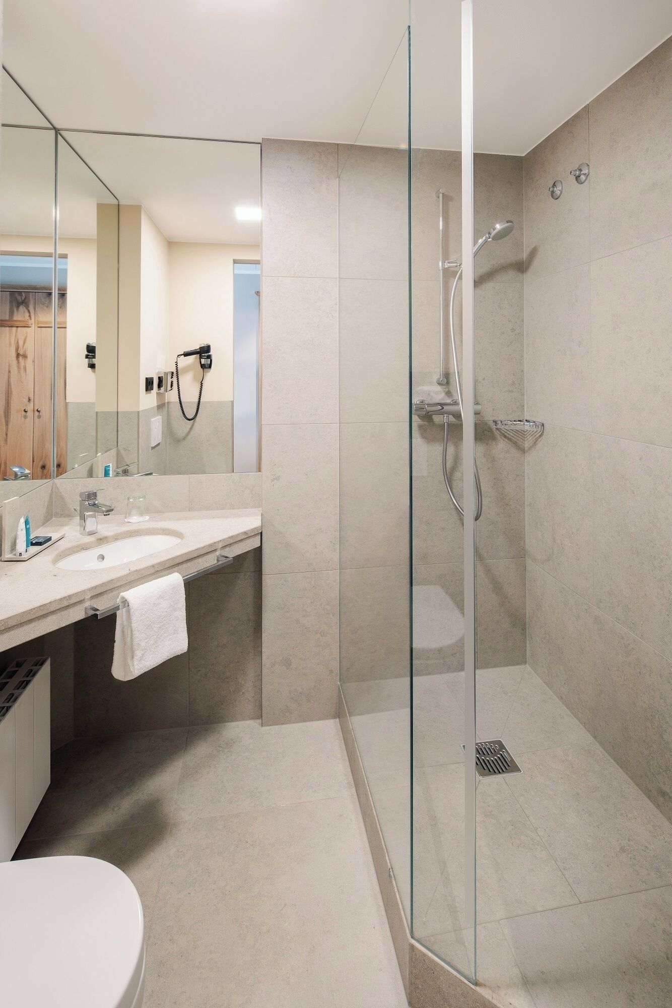 A modern bathroom with a glass-enclosed shower, a vanity with a sink, and a mirror.