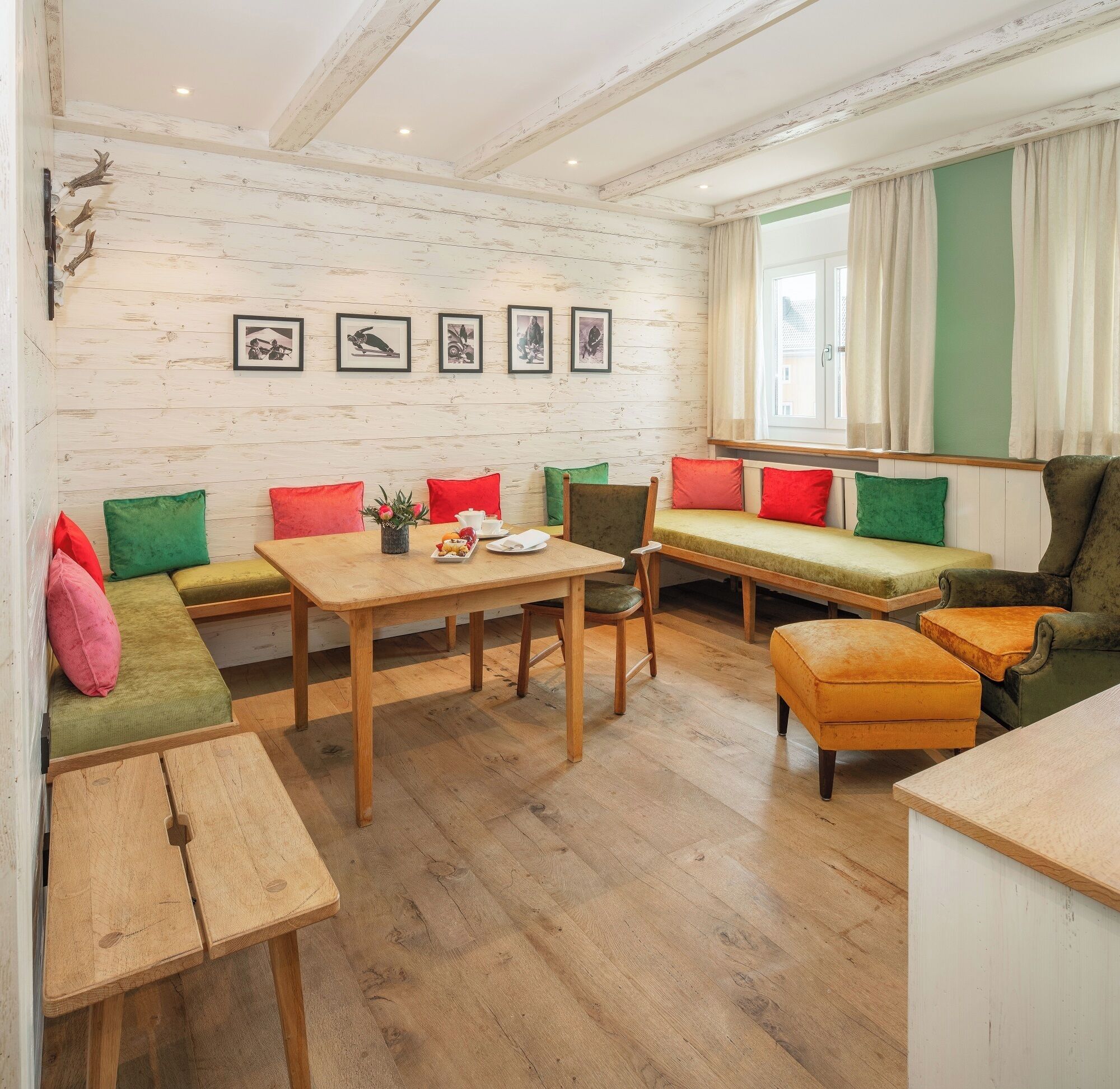 A cozy room with a wooden table, a bench with cushions, and a sofa.