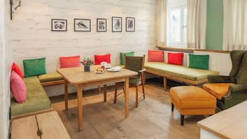 Una habitación acogedora con una mesa de madera, un banco con cojines y un sofá.
