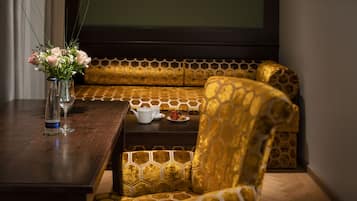 A seating area with a sofa and a chair, a table with a vase of flowers, a teapot, and a cup.