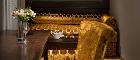 A seating area with a sofa and a chair, a table with a vase of flowers, a teapot, and a cup.
