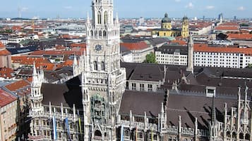 Una plaza histórica con una imponente torre del reloj, rodeada de edificios ornamentados y una multitud animada.