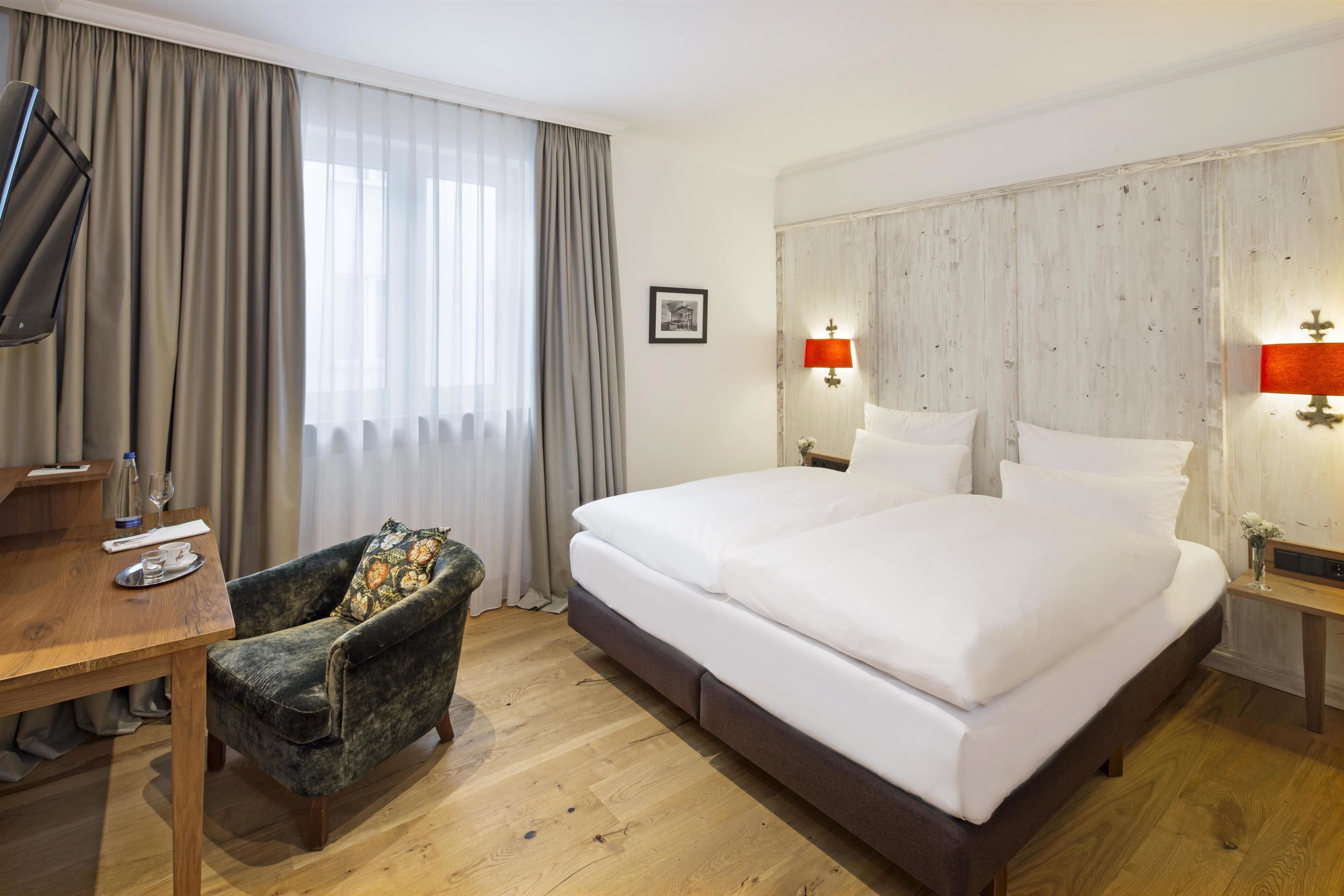 Ein Hotelzimmer mit einem großen Bett, einem Holztisch, einem Stuhl und einem Fernseher.
