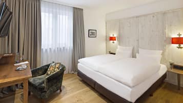 Ein Hotelzimmer mit einem großen Bett, einem Holztisch, einem Stuhl und einem Fernseher.