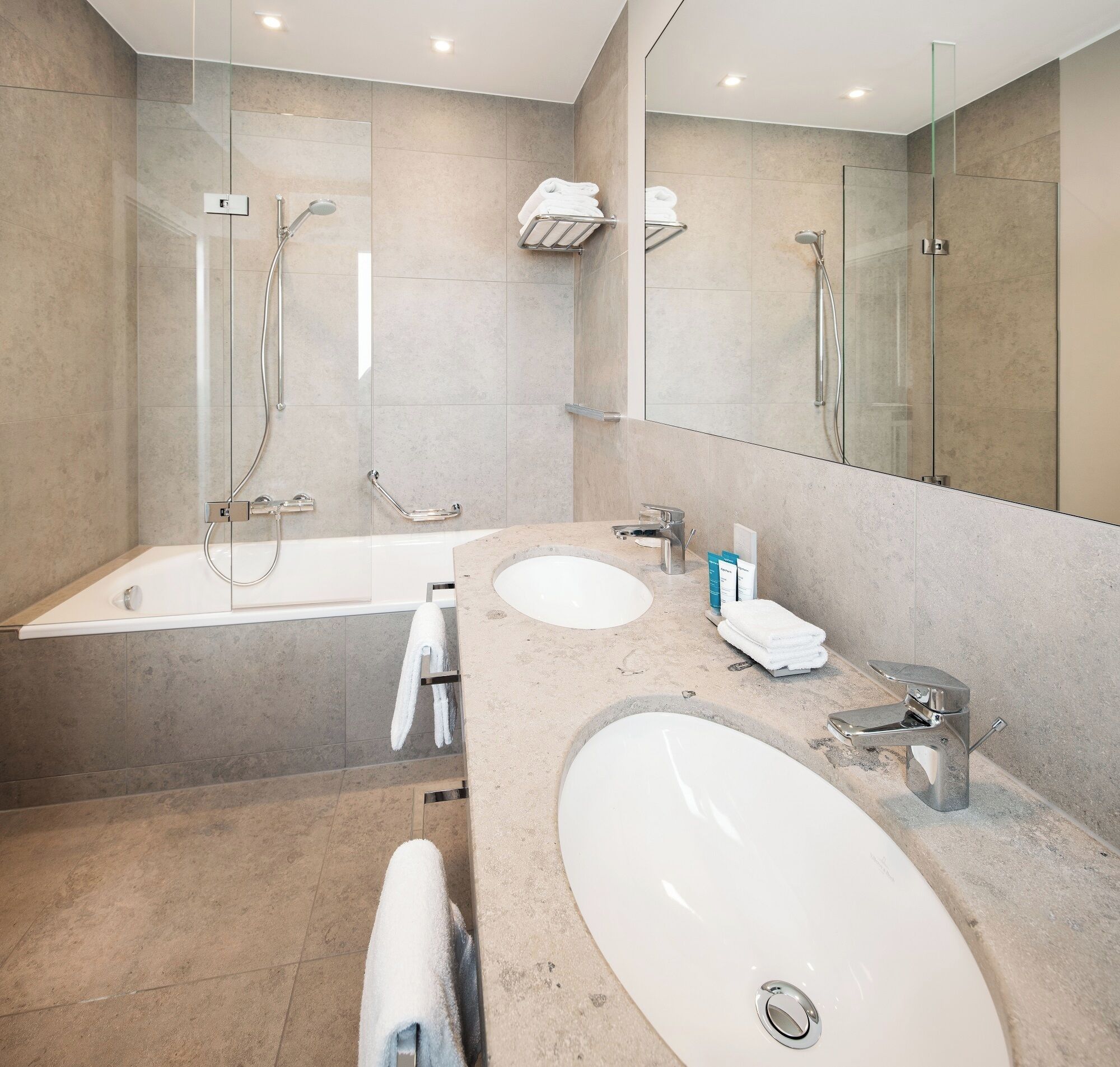 Ein modernes Badezimmer mit Badewanne, zwei Waschbecken und einer Duschkabine aus Glas.