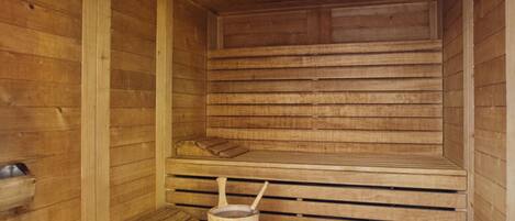 Una sauna de madera con bancos, un balde y toallas.