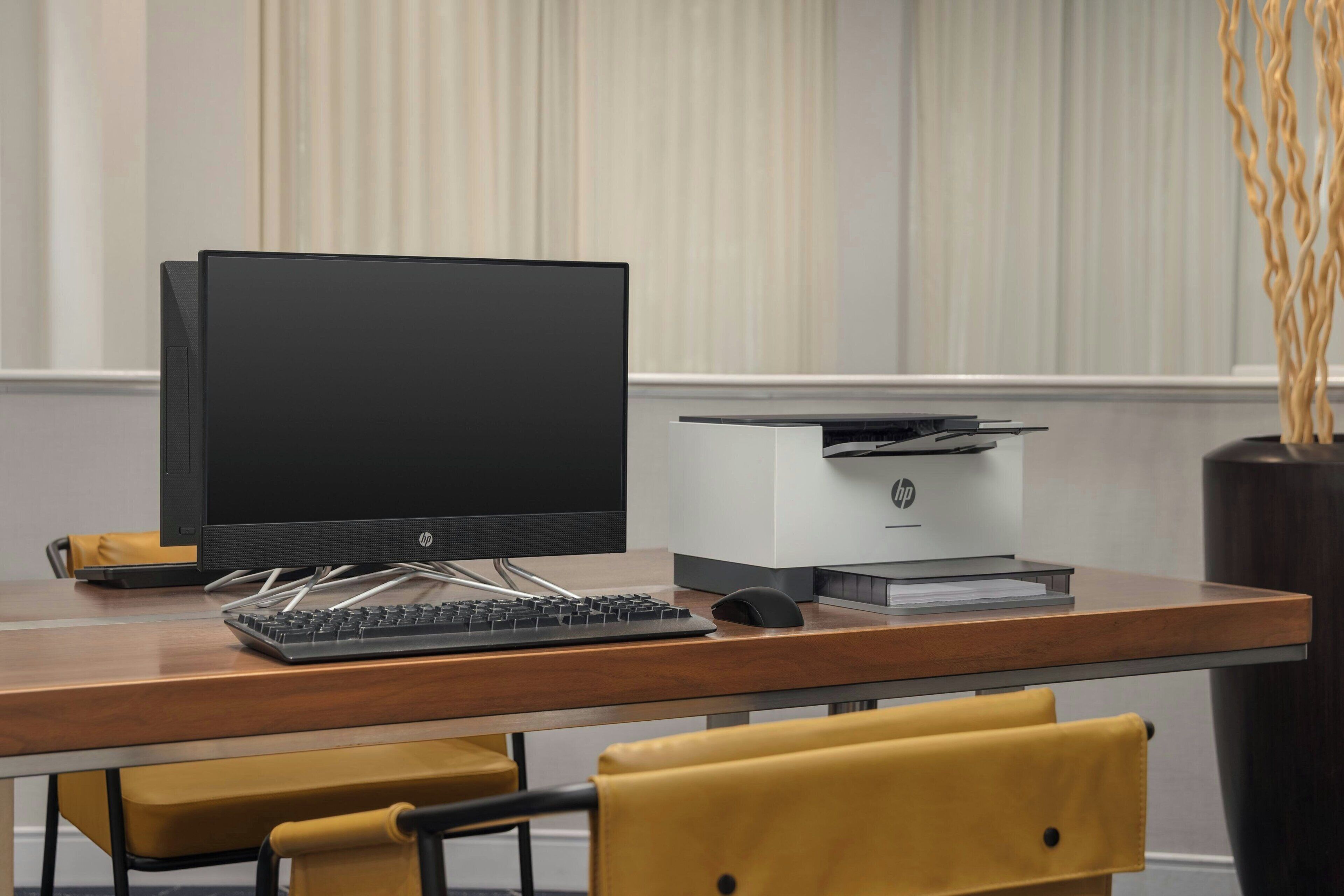 A modern office desk with a computer, keyboard, and printer.