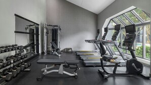 Une salle de sport équipée de machines de musculation, de tapis de course et d’haltères.