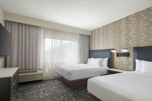 A hotel room with two beds, a desk, a TV, and a large window with curtains. - Courtyard by Marriott Dallas-Fort Worth/Bedford (Bedford)