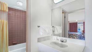 Un baño con lavamanos blanco, espejo y ducha con cortina.