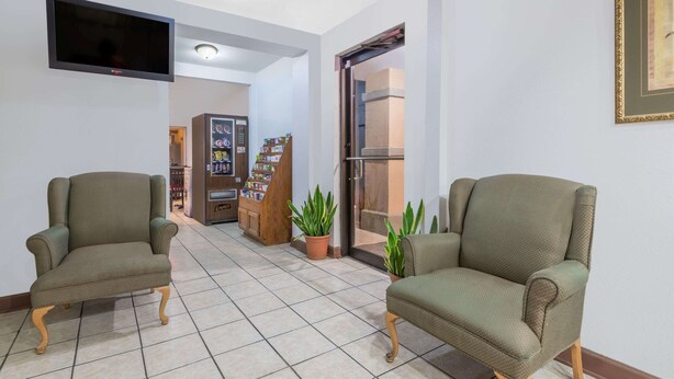 Un vestíbulo con dos sillones, un televisor, una máquina expendedora y una puerta que da al exterior.
