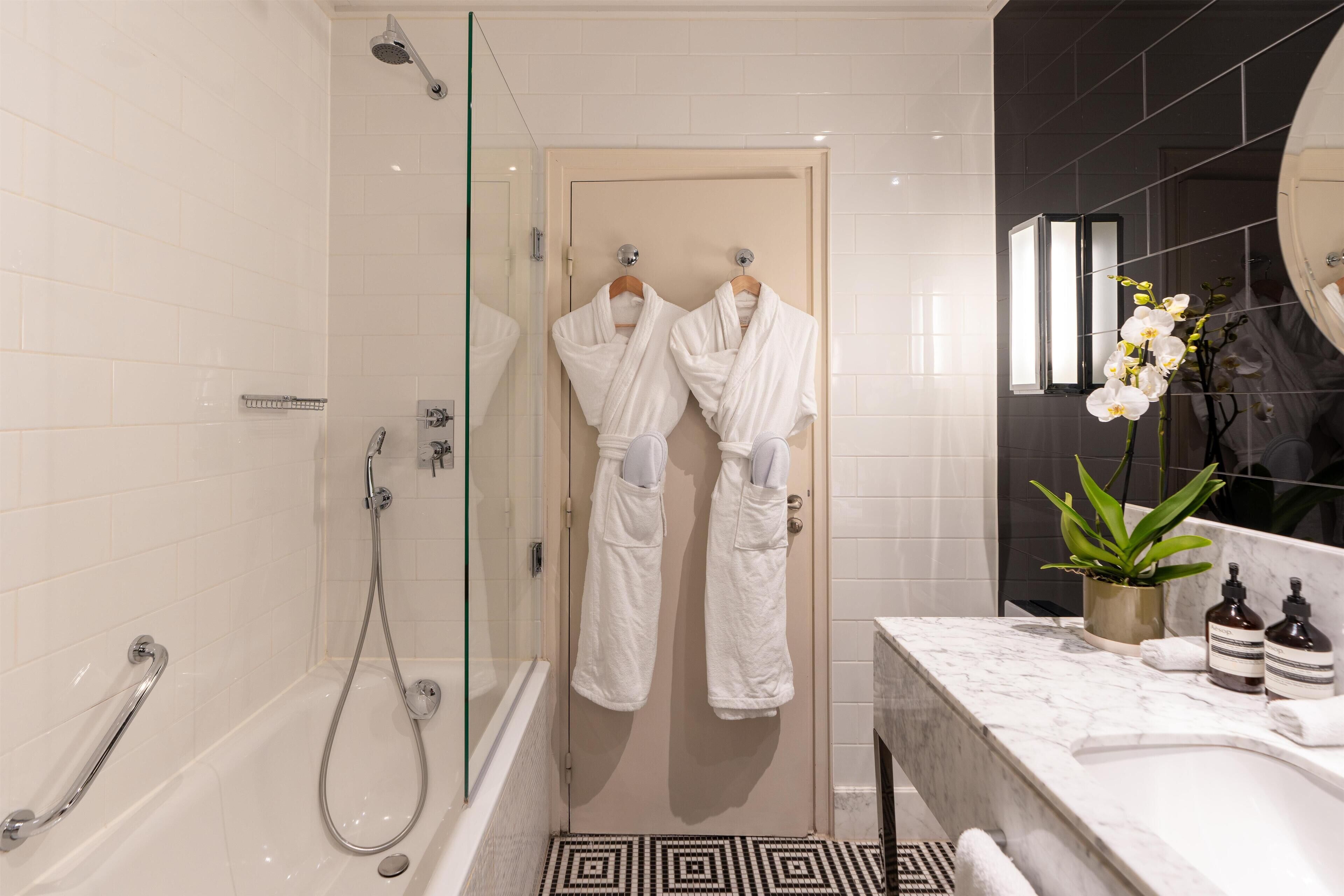 Een moderne badkamer met een douchecabine van glas, een badkuip en een marmeren wastafelmeubel.