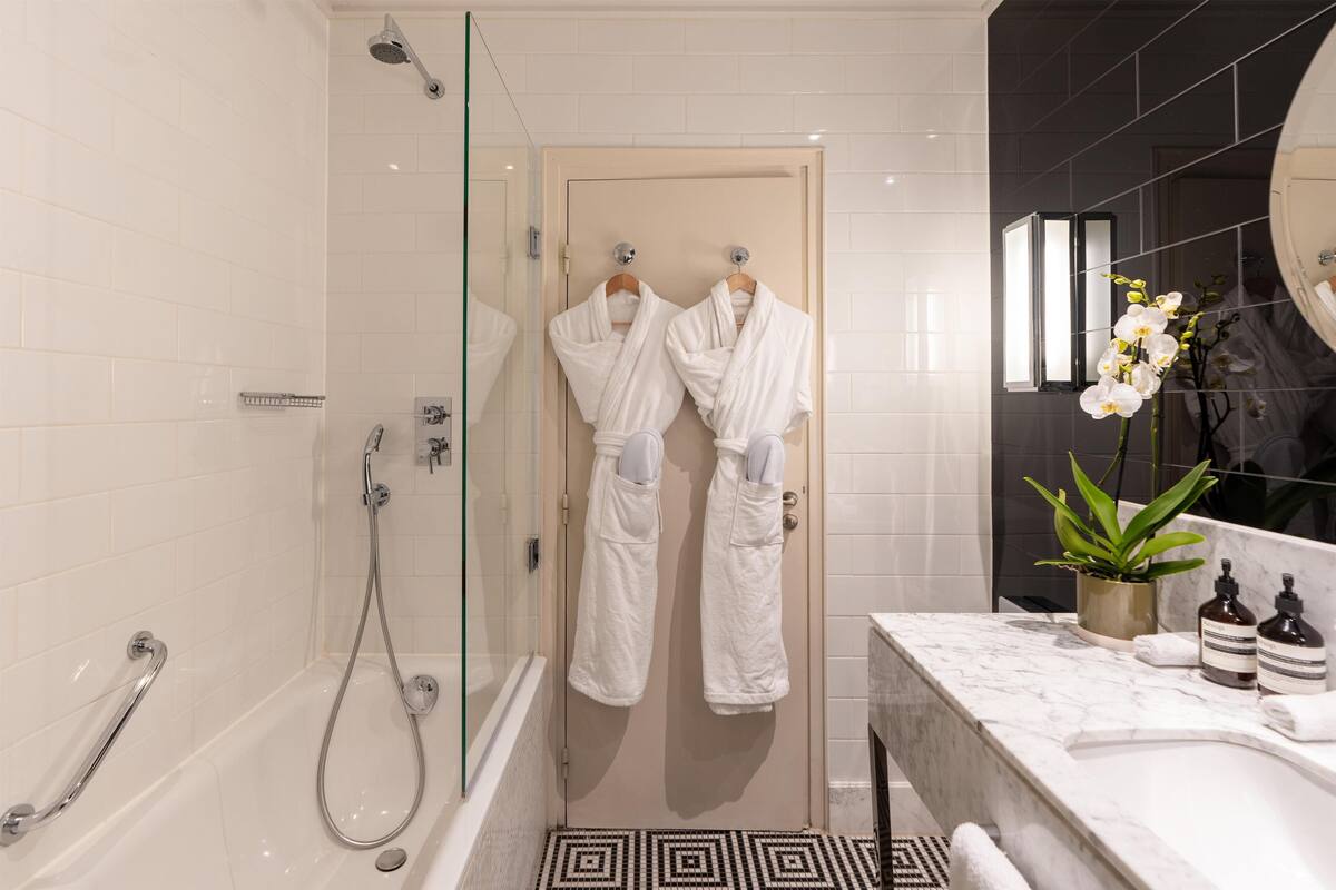 Une salle de bain moderne dotée d’une douche à parois de verre, d’une baignoire et d’un meuble-lavabo en marbre.