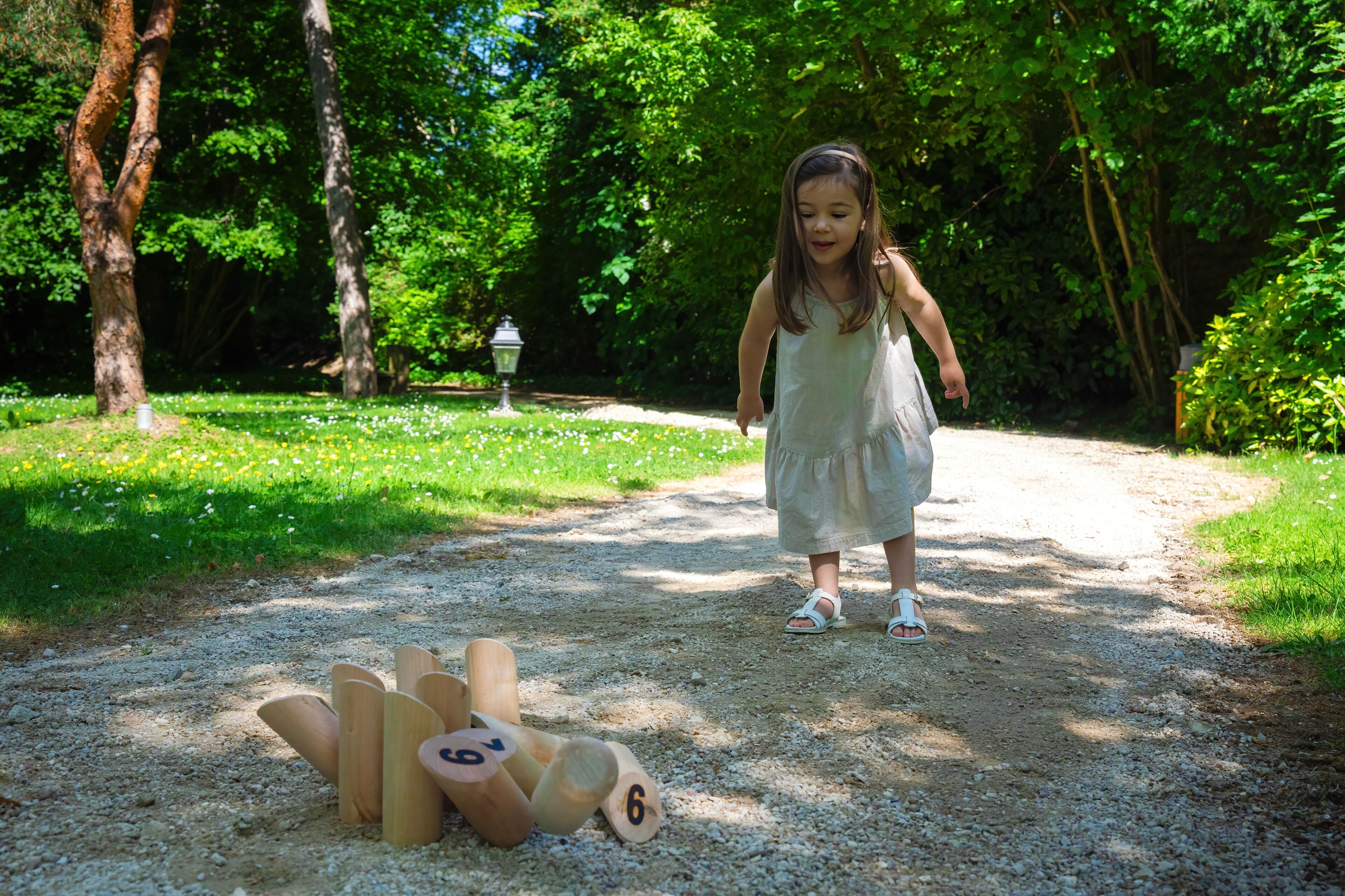 Ein Kind spielt mit Holzwürfeln auf einem Kiesweg in einem Park.