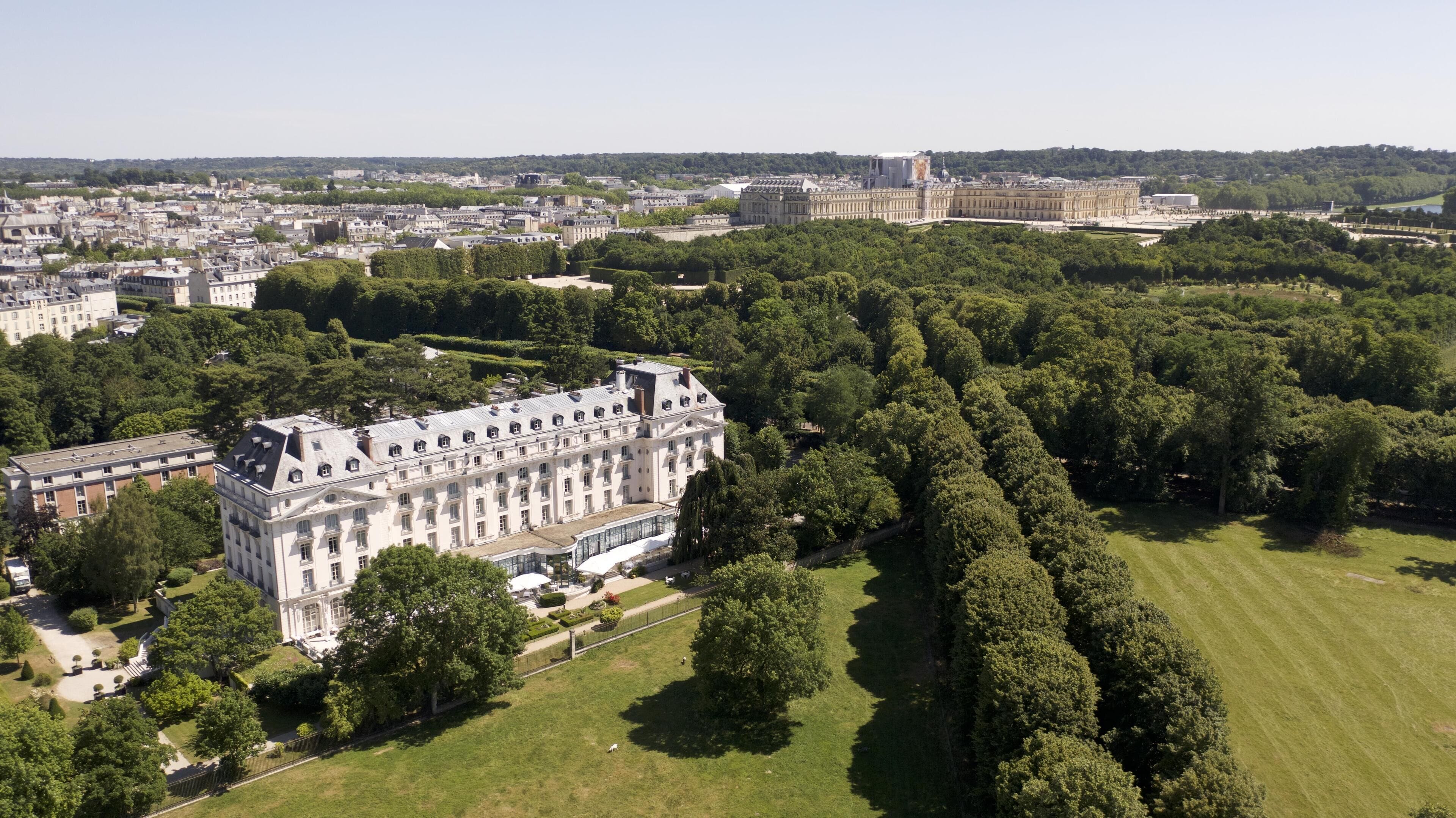 An aerial view of a large, historic building surrounded by lush green parks and other buildings.