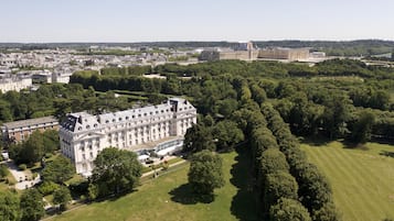 An aerial view of a large, historic building surrounded by lush green parks and other buildings.