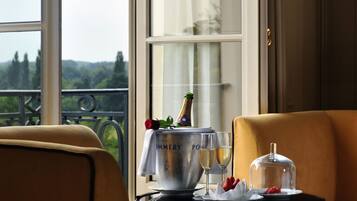 Une chambre avec vue sur un balcon, une table avec une bouteille de champagne, des verres et un objet décoratif.