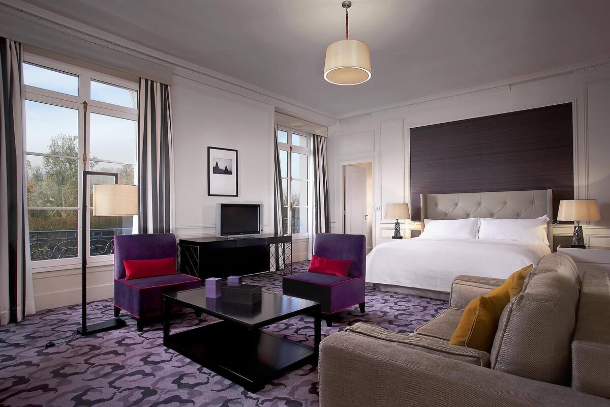 Une chambre d’hôtel comprenant un lit, deux fauteuils, un canapé, un bureau et un téléviseur.