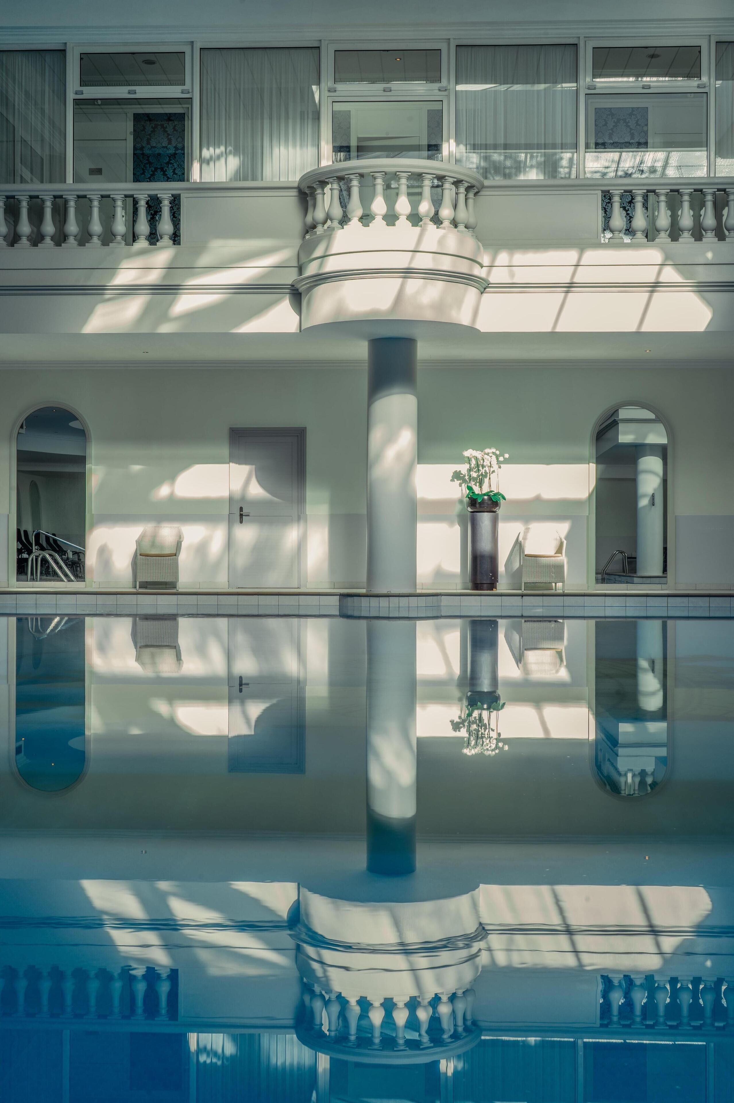 A multi-level building with a central column, balconies, and a reflective pool.