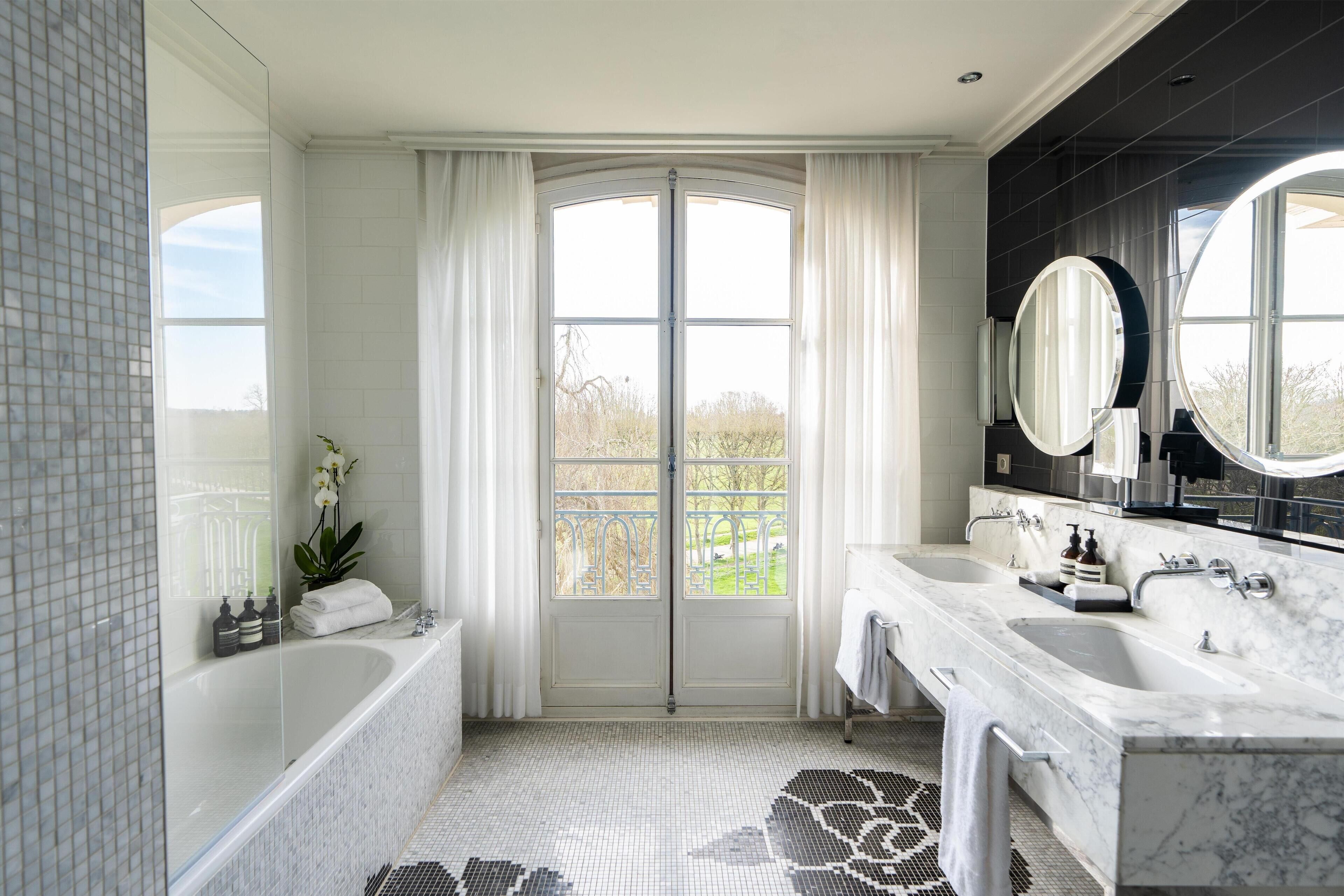 A modern bathroom with a large bathtub, two sinks, and a large mirror.