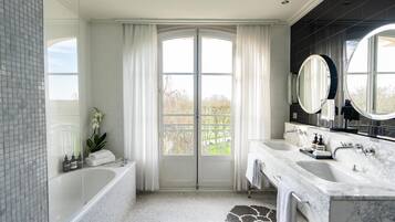 A modern bathroom with a large bathtub, two sinks, and a large mirror.