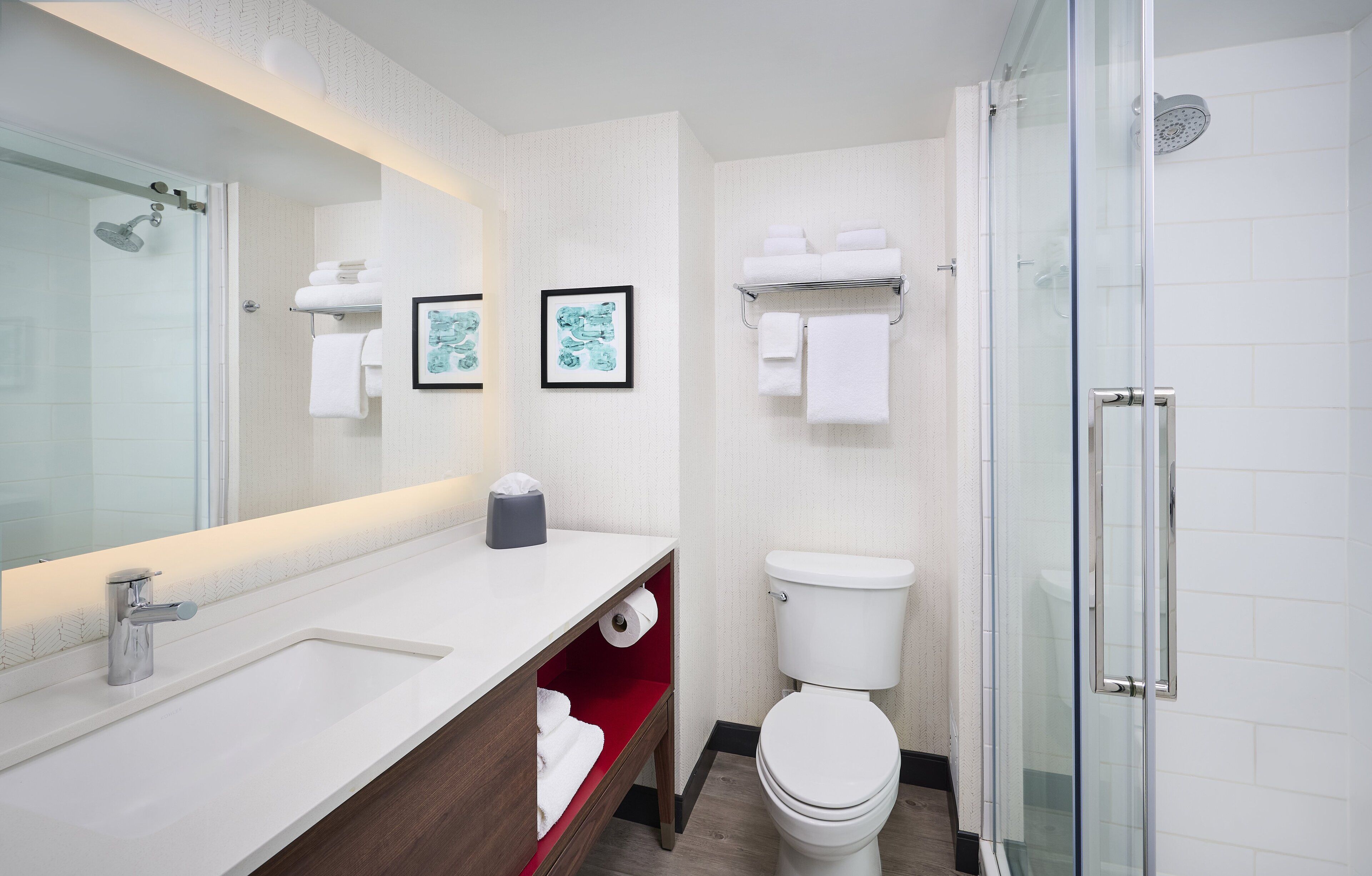 A modern bathroom with a glass shower enclosure, a white sink with a mirror, and a toilet with a glass partition.