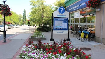 A visitor information center with a signboard, flower beds, and bicycles parked outside.