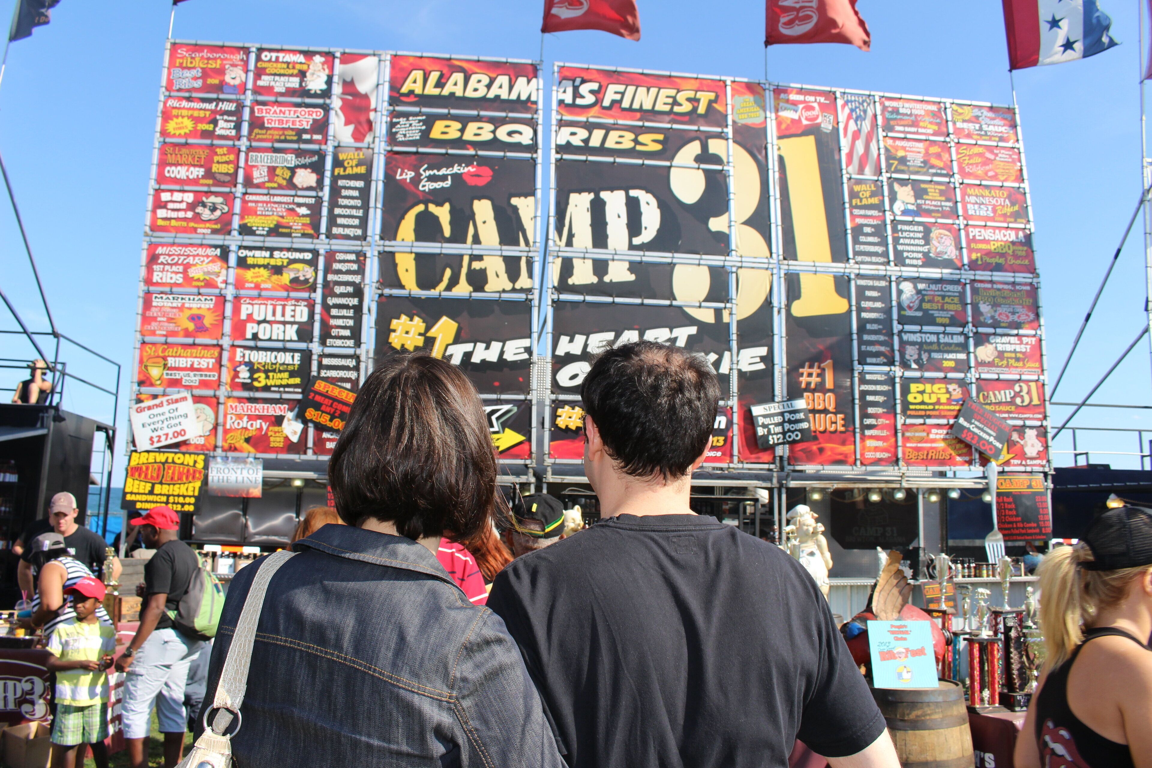 Un grand panneau publicitaire extérieur présentant diverses publicités pour des produits alimentaires et affichant en évidence l’inscription « Camp 31 ».