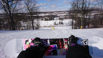 A snowboarder's feet on a snowboard with a view of a snowy landscape and a ski lift in the background.