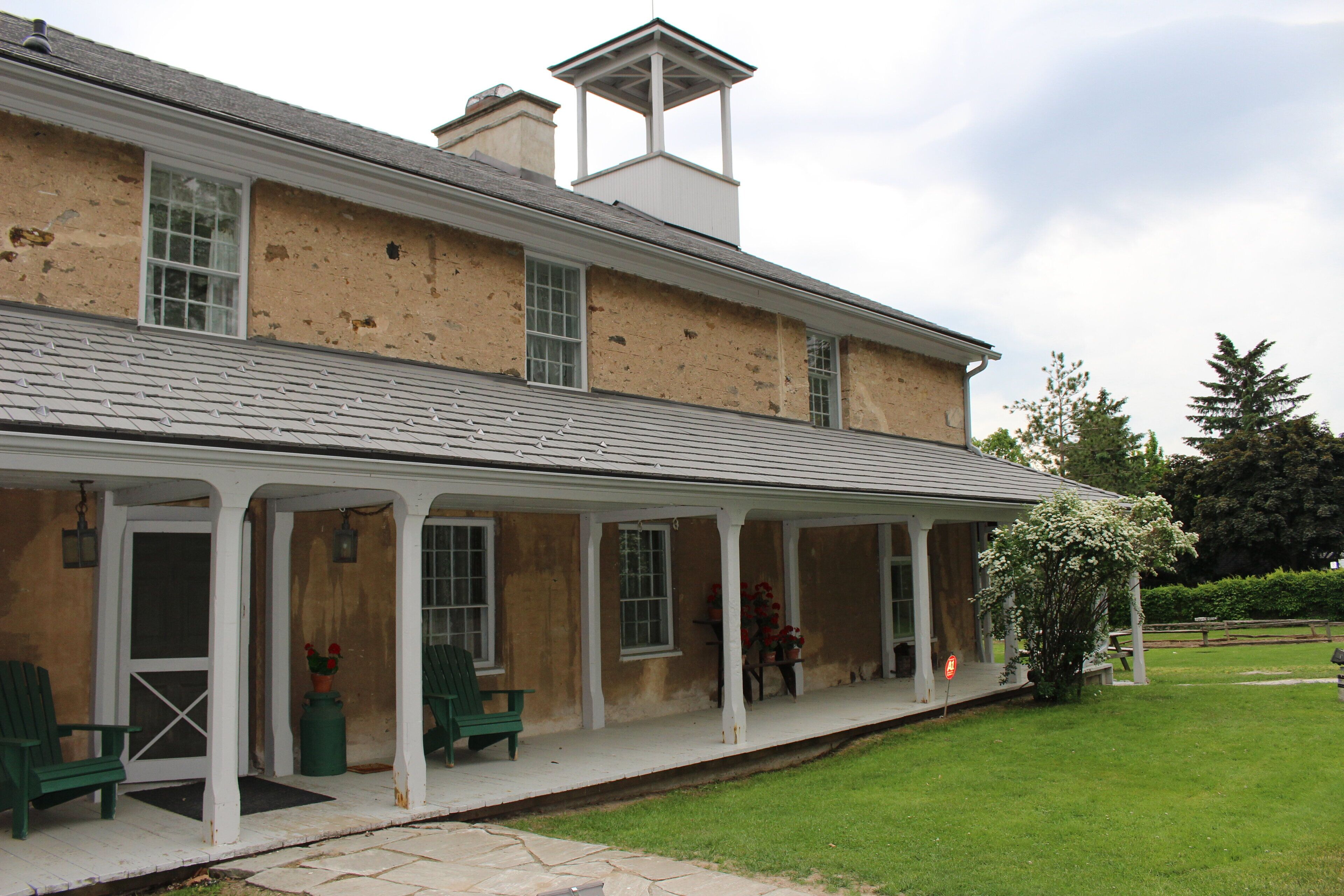 A two-story building with a covered porch, multiple windows, and a chimney.