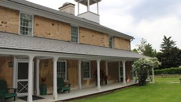 A two-story building with a covered porch, multiple windows, and a chimney.