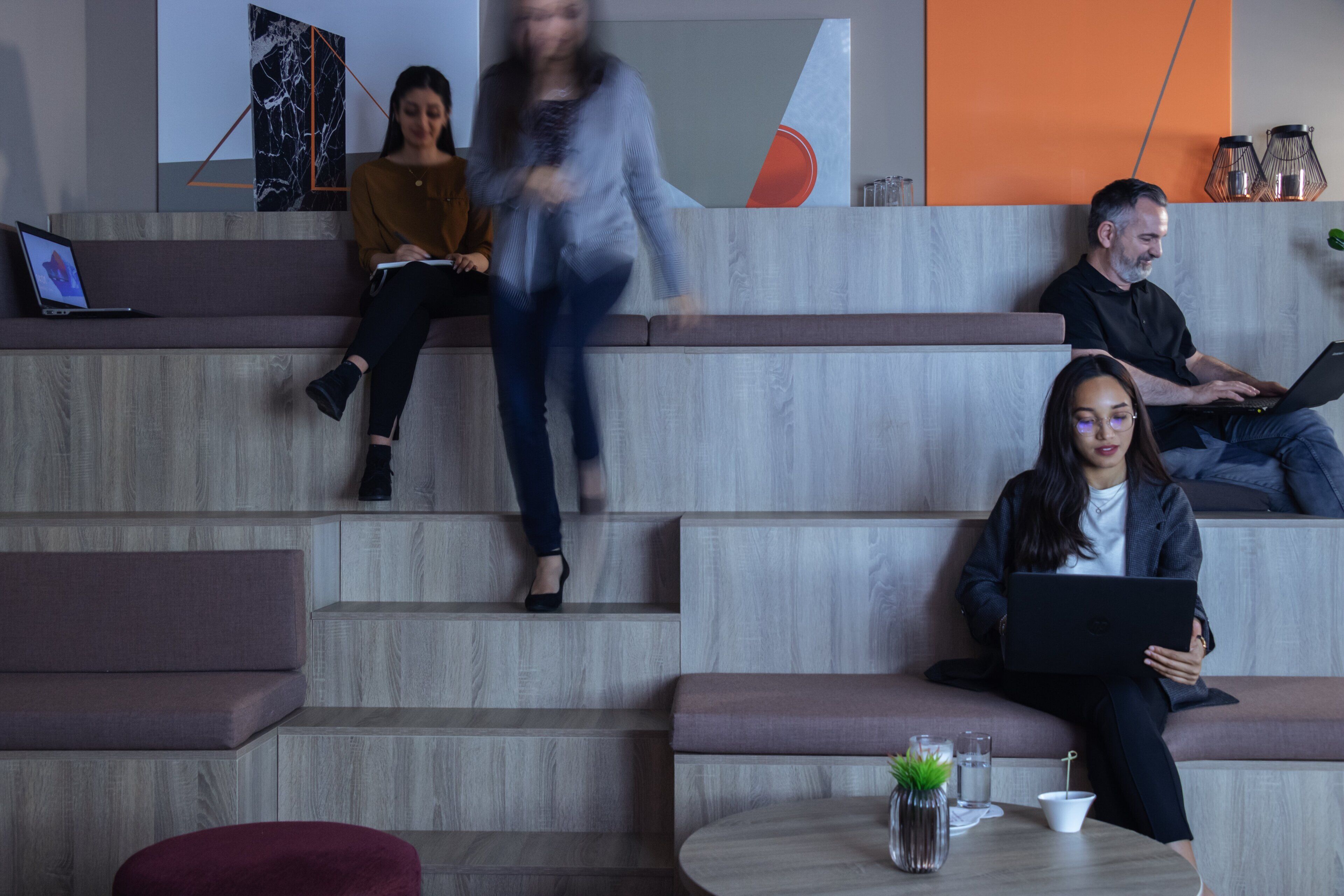 Un espace détente moderne, doté de sièges et d’une table, où l’on trouve un ordinateur portable, un téléphone intelligent et un verre d’eau.