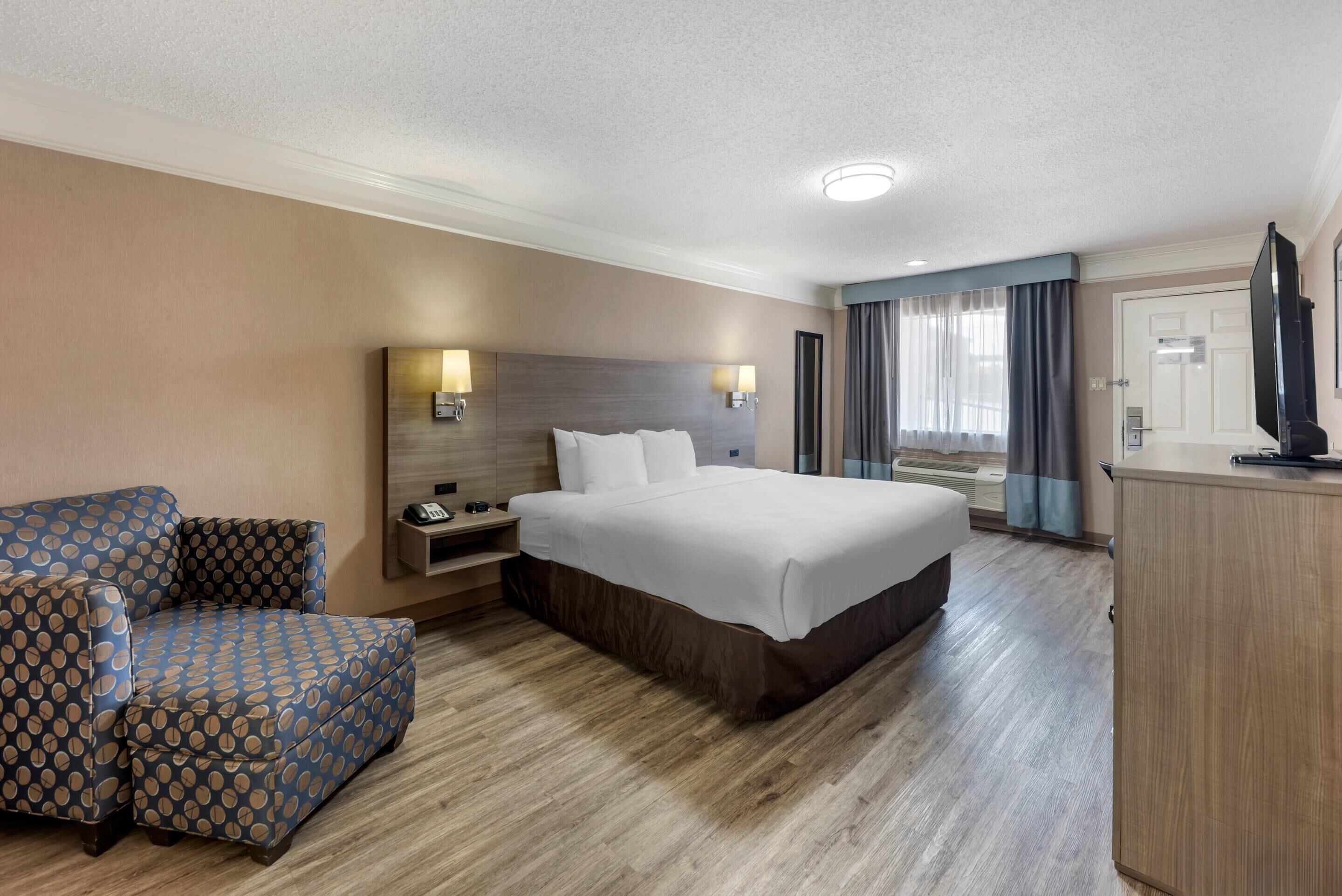 Ein Hotelzimmer mit einem großen Bett, einer Couch, einem Schreibtisch und einem Fernseher.