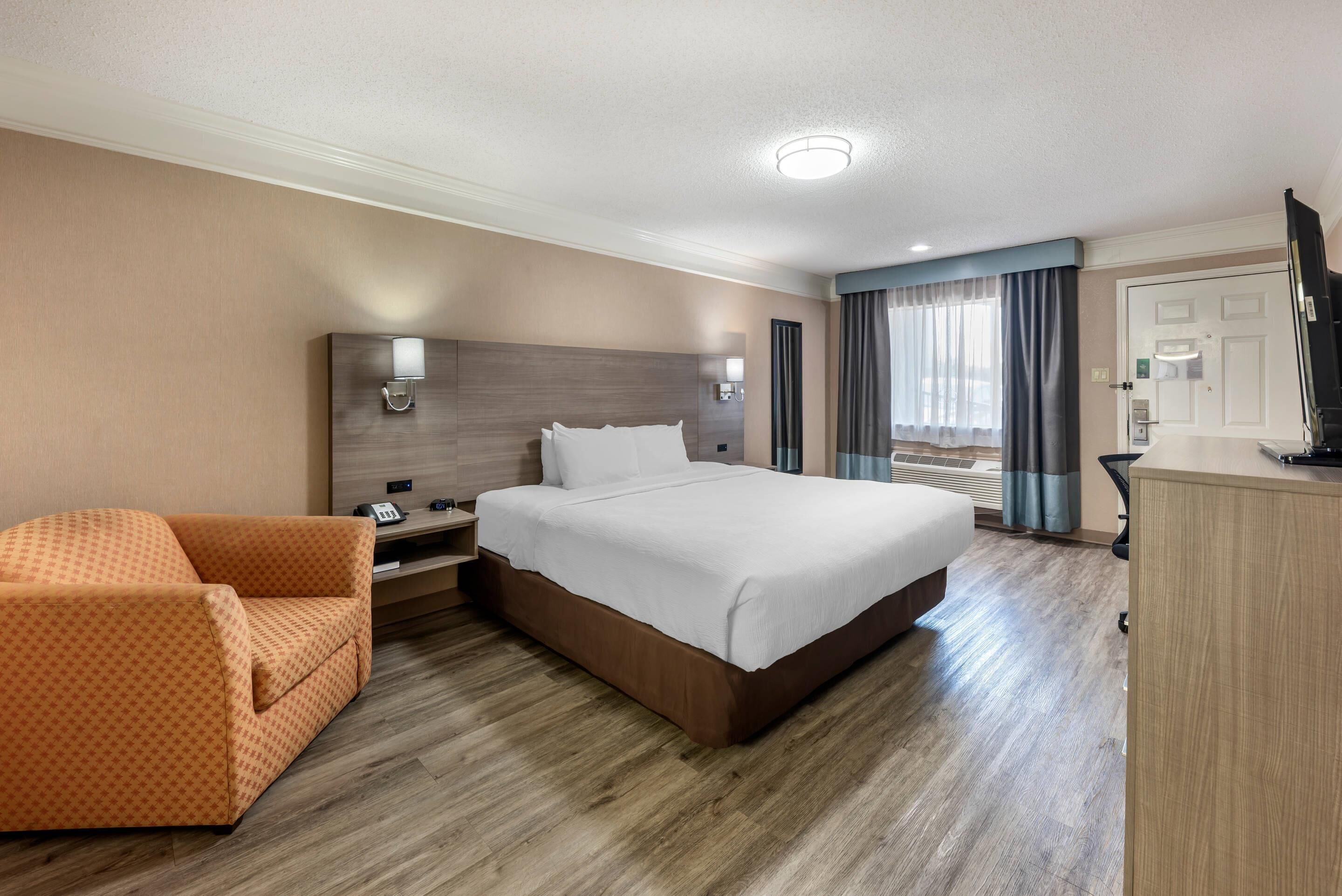 Una habitación de hotel con una cama grande, un sofá, un escritorio y una televisión.