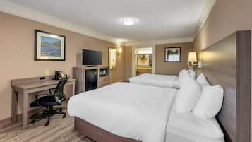 Habitación de hotel con una cama grande, un escritorio con computadora, un televisor y un cuadro en la pared.