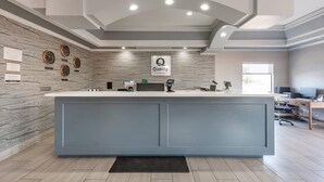 A reception area with a marble wall, a large reception desk, and a sign that reads "Quality by Choice Hotels". - Quality Inn Near Lake Marble Falls (Marble Falls)