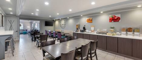 Una cocina y comedor modernos con una isla central, mesas y sillas.