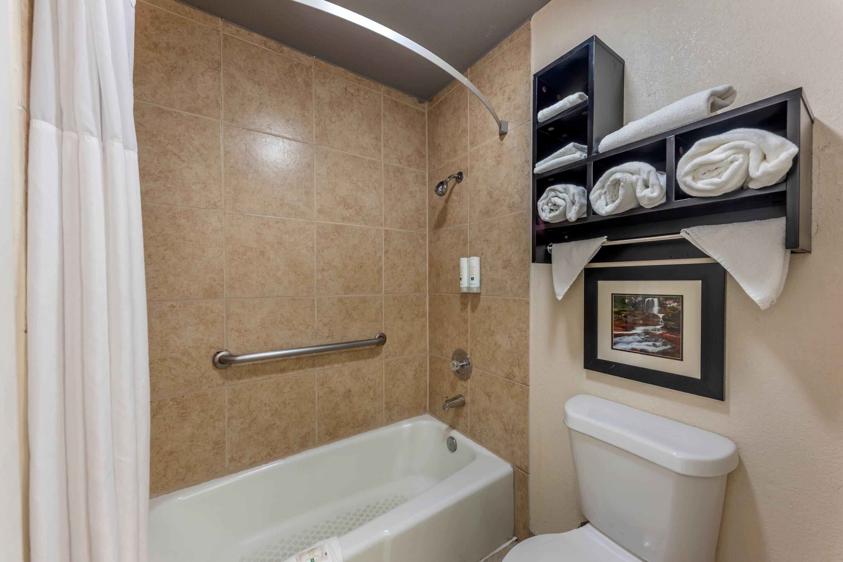 A bathroom with a bathtub, a toilet, and a shelf with towels.