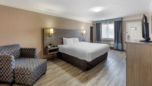 A hotel room with a bed, a sofa, a desk, and a television. - Quality Inn Near Lake Marble Falls (Marble Falls)