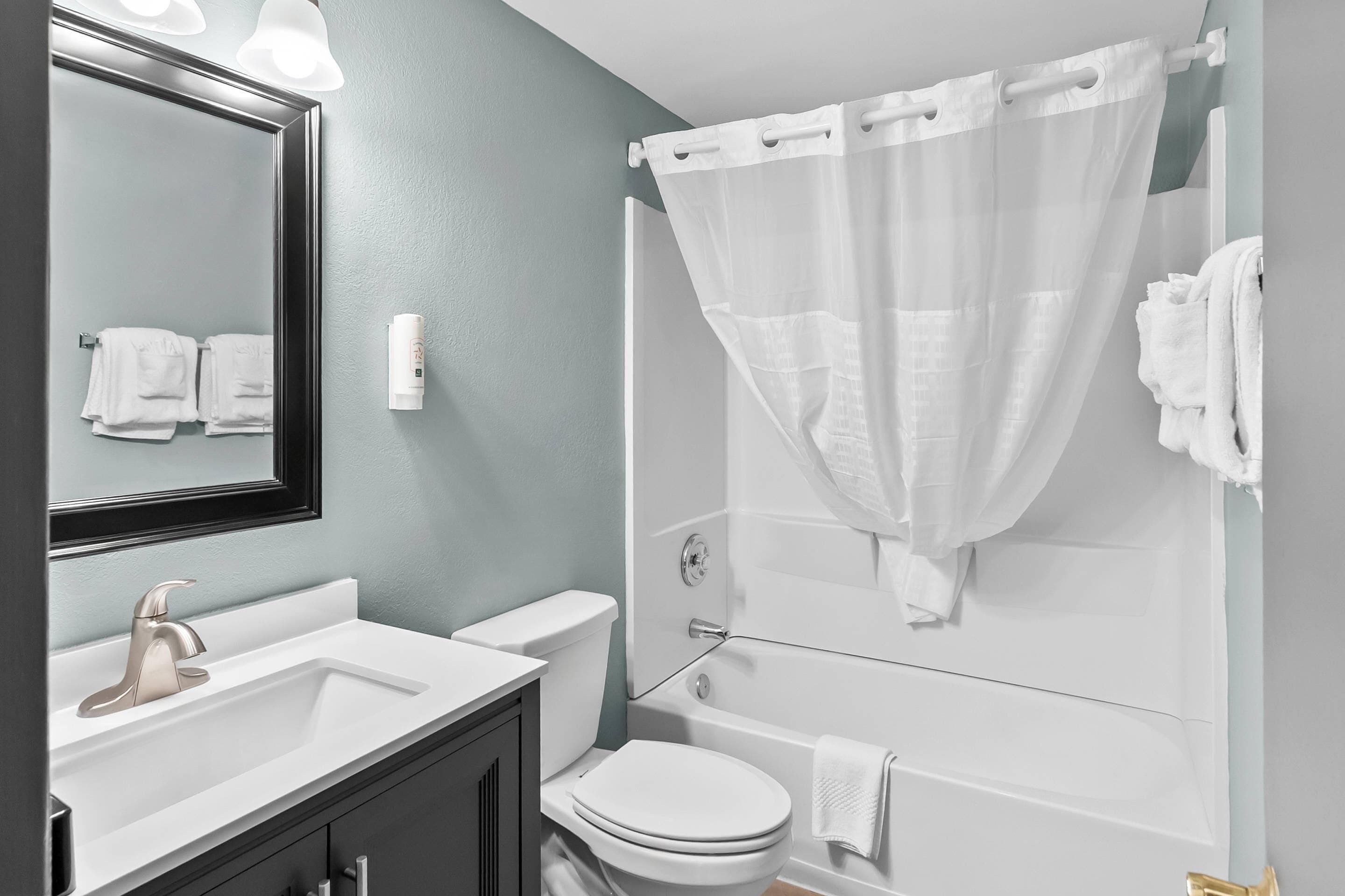A bathroom with a white sink, a toilet, and a shower with a white curtain.